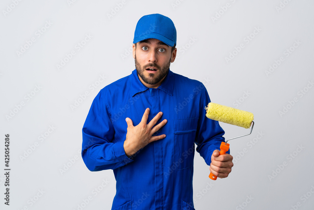 Painter man holding a paint roller isolated on white background pointing to oneself