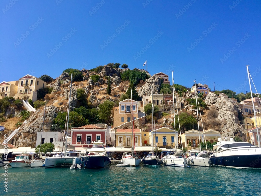 Symi island view from the sea. Aegean Sea. Marina, yachts, colourful houses, mountain. Boats in the harbor. Greece. Date of photo is 18.08.2019
