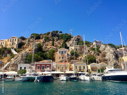 Symi island view from the sea. Aegean Sea. Marina, yachts, colourful houses, mountain. Boats in the harbor. Greece. Date of photo is 18.08.2019 © Alla