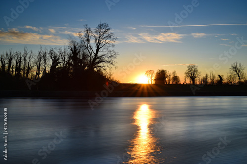 beautiful sunset on the river, colors, lights and reflections surround this wonderful countryside landscape
