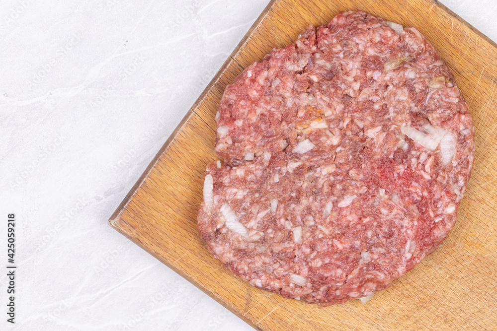 Top view of raw minced meat pljeskavica on the wooden board with copy space Top view of raw minced meat pljeskavica on the wooden board with copy space