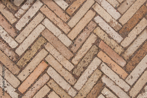 The texture of paving stones. Herringbone pattern on the road in the park. Zigzag paving stone covered with gravel.