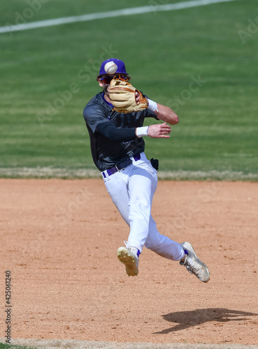 Action photo of athletic high school baseball player making an amazing play during a baseball game
