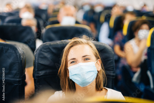 jeune femme heureuse de prendre l'avion malgré le port du masque. Elle se trouve dans un avion bondé. photo