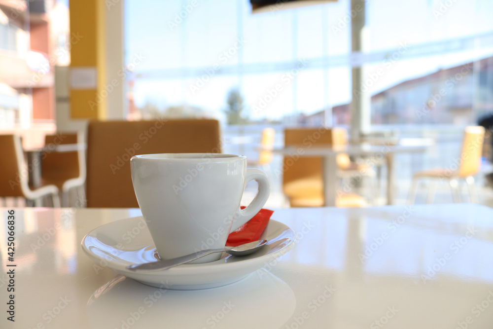 Coffee cup on a table in a cafe.
Close-up of a cup of coffee, in the interior of a cafe, in daylight.