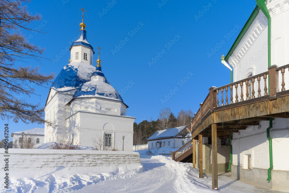 View of one of the churches of the ancient 17th century nunnery near Tobolsk (Russia) on a frosty winter day. Blue and gold domes and white brick walls with patterned retro brickwork. Blue sky View of one of the churches of the ancient 17th century nunnery near Tobolsk (Russia) on a frosty winter day. Blue and gold domes and white brick walls with patterned retro brickwork. Blue sky