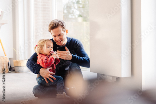 Papa et enfant regardent se téléphone portable, complices intérieur heureux photo