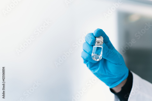 hand with blue gloves holding a glass container with covid-19 vaccine, flu, measles, corona. space for copy space, horizontal picture