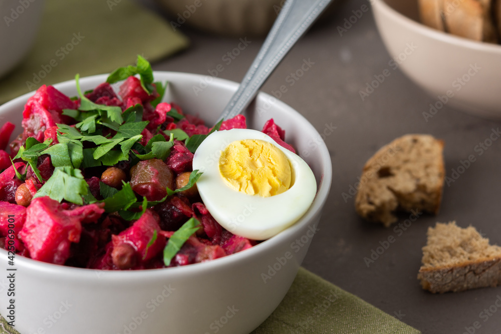 Russian salad vinaigrette in plates with boiled egg and black bread, salad of boiled and pickled vegetables and canned green peas Russian salad vinaigrette in plates with boiled egg and black bread, salad of boiled and pickled vegetables and canned green peas
