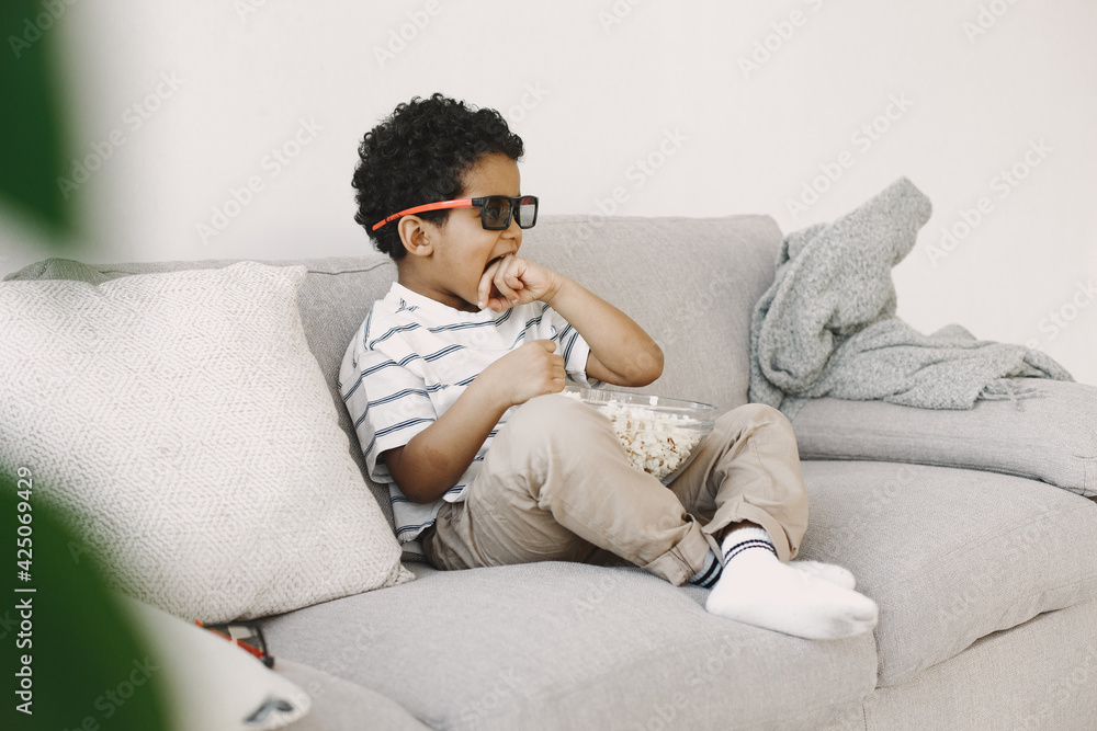 Boy watching a movie on couch in 3d glasses with popcorn Boy watching a movie on couch in 3d glasses with popcorn