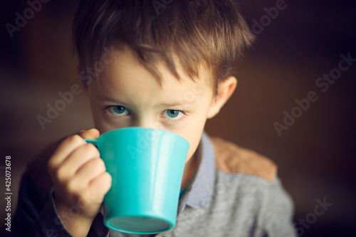 Chłopiec pije herbatę z kubka.