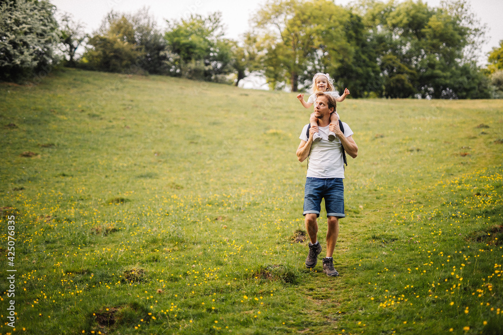 Petite fille sur les épaules de son papa lors d'une balade en été à la campagne Petite fille sur les épaules de son papa lors d'une balade en été à la campagne
