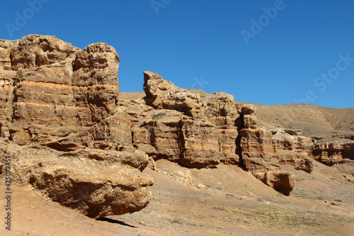 Sandy-clay red rocks with cracks and relief in the Charyn canyon, a wall of beautiful relief rocks, summer, sunny