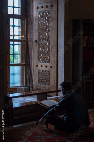 Blue mosque, Istanbul \ Turkey - March 3, 2017: A man siting reciting Quran inside Blue mosque (Sultan Ahmed mosque)