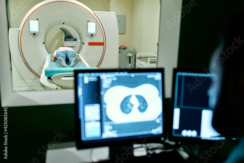In the medical laboratory, the patient undergoes an MRI or CT scan under the supervision of a radiologist, in the control room, the doctor observes the procedure and monitors the scan results.