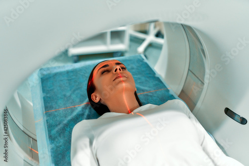 Foto Portrait of a patient lying on CT or MRI, the bed moves inside the machine, scanning her body and brain