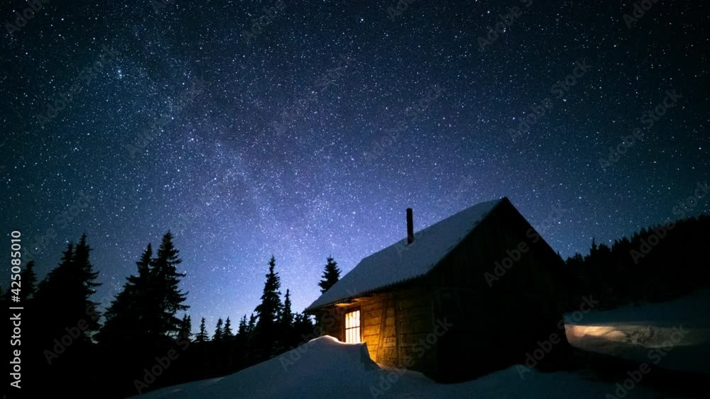 Time lapse milky way moving over mountain hut and pine forest. Starry night sky seen from a cozy wooden log cabin. Relax and freedom concept Time lapse milky way moving over mountain hut and pine forest. Starry night sky seen from a cozy wooden log cabin. Relax and freedom concept