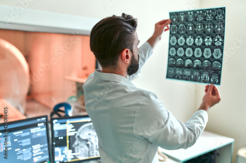 A doctor examines an MRI scan of a patient's brain in a control room. Examination in the modern laboratory of the hospital. Health care concept.