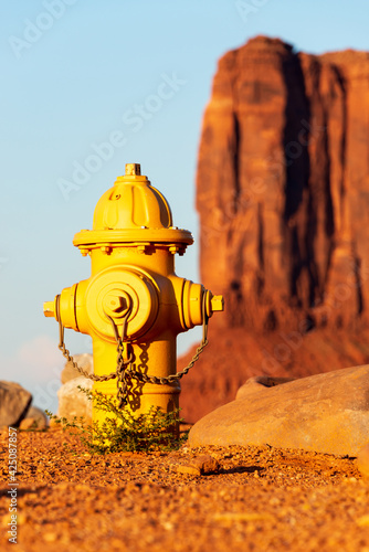 Gelber Hydrant mit einem großen roten Felsen im Hintergrund im Monument Valley in Arizona in den USA