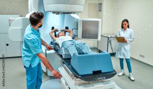 A young woman is undergoing radiation therapy for cancer under the supervision of doctors in a modern cancer hospital. Cancer therapy  advanced medical linear accelerator.