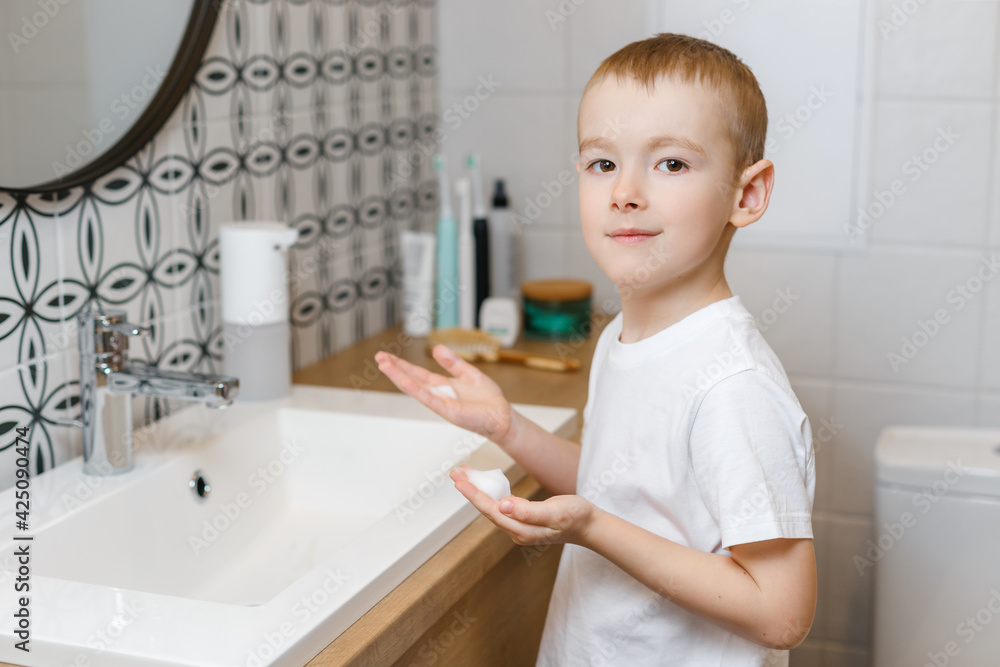 Boy washing hands in bathroom using sensor soap dispenser. Kid hygiene, healthcare and body care Boy washing hands in bathroom using sensor soap dispenser. Kid hygiene, healthcare and body care