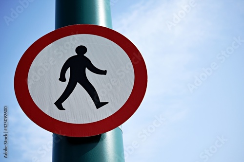 UK road sign no pedestrians allowed, against a blue cloudy sky.