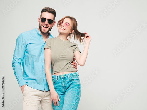 Smiling beautiful woman and her handsome boyfriend. Happy cheerful family having tender moments on grey background in studio.Pure cheerful models hugging.Embracing each other in sunglasses