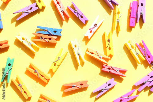 Decorative multicolored wooden clothespins on a yellow background. Flat lay composition 