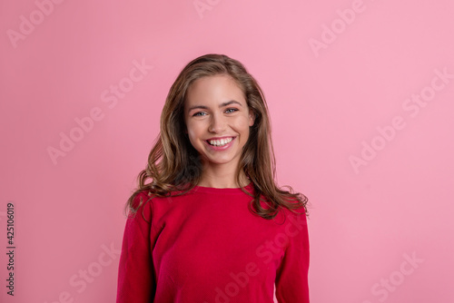 portrait of a beautiful young blonde girl in a red jacket on a pink background. happy teen girl smiles © Асель Иржанова