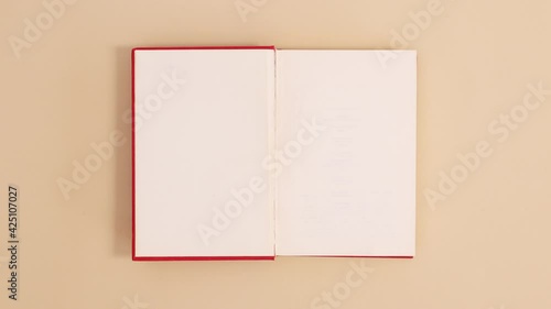 Wallpaper Mural Red hardcover vintage book appear and open with copy space on beige background. Stop motion flat lay Torontodigital.ca