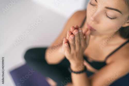 Meditation at home Asian woman praying mantra with prayer hands at mouth chakra saying zen prayer meditating at yoga class. Inner peace stress free mindfulness. photo