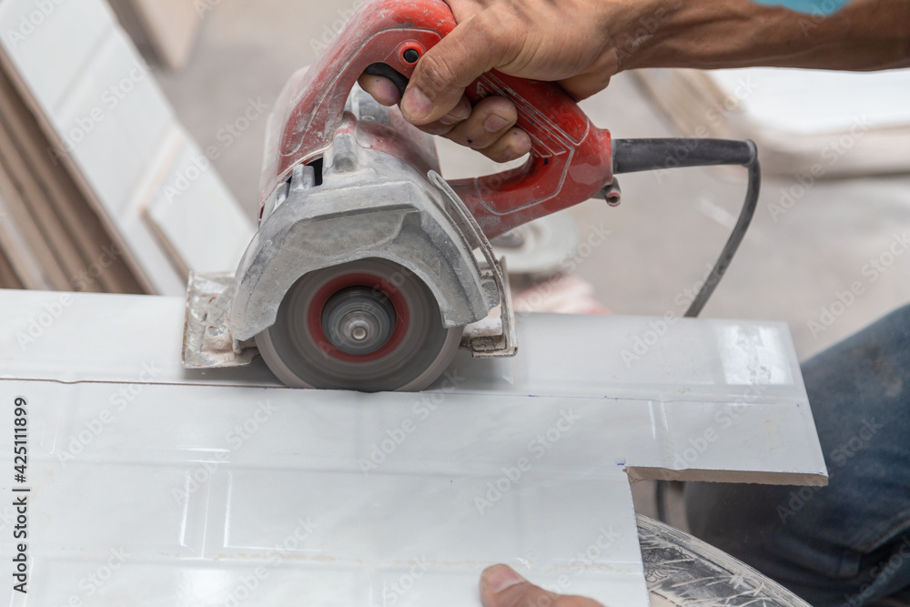 Closeup of worker cutting white tile with blade for assembly, copy space Closeup of worker cutting white tile with blade for assembly, copy space