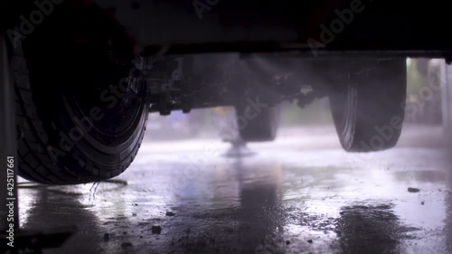 Image of man cleaning under a truck with a power washer at a repair shop.