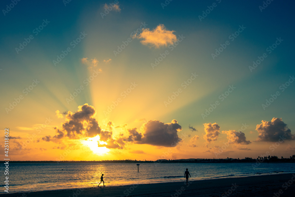 Silhueta de pessoas caminhando na praia de Serambi durante o pôr-do-sol. Silhueta de pessoas caminhando na praia de Serambi durante o pôr-do-sol.