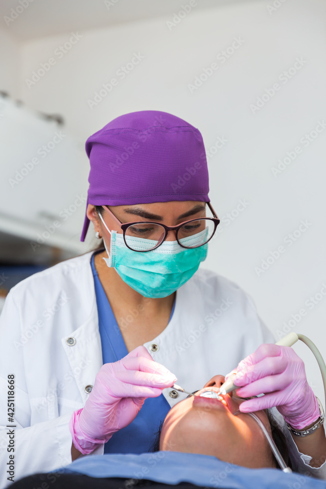 Naklejka premium Dentist with glasses and mask during the patient's treatment in a dental office