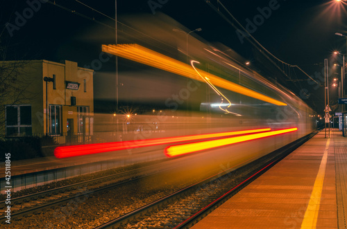 The lights of a running train at a train station.
