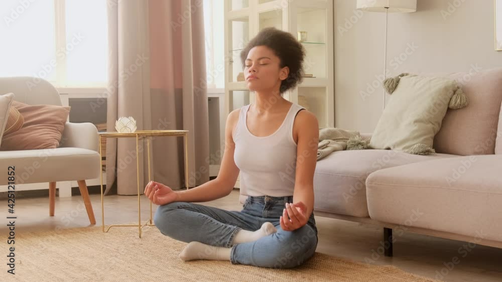 Black african american woman meditating while sitting at home. Calm female taking deep breath and relaxing with eyes closed. No stress and peace of mind. Black african american woman meditating while sitting at home. Calm female taking deep breath and relaxing with eyes closed. No stress and peace of mind.