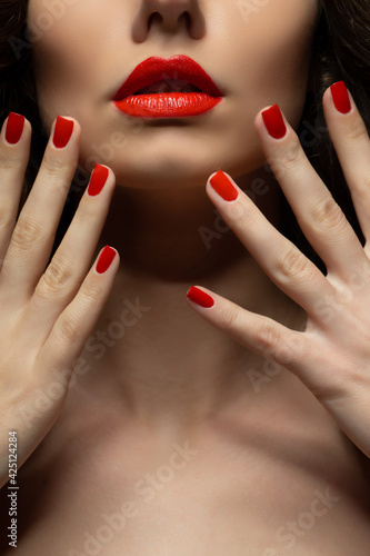 Beautiful girl showing red manicure nails . makeup and cosmetics. Brunette girl with long and shiny curly hair