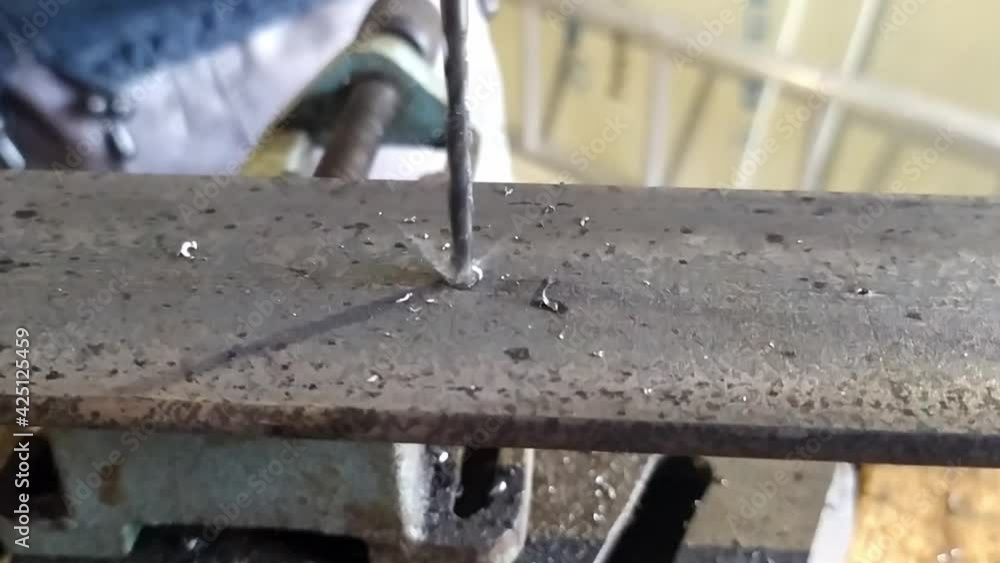 Slow motion detail of a drill bit drilled into a steel piece of iron, a drill in a home workshop makes holes in the iron Slow motion detail of a drill bit drilled into a steel piece of iron, a drill in a home workshop makes holes in the iron