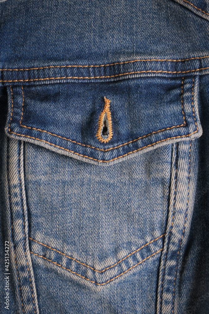 Denim pocket with a metal button on a blue jacket close-up with rough seams. High quality photo Denim pocket with a metal button on a blue jacket close-up with rough seams. High quality photo