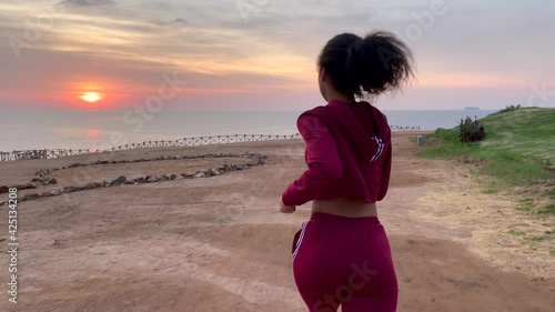 Notice the beauty around you. Active young woman running to the edge of the cliff at sunrise. Slow motion. Body positive, healthy lifestyle, nature concept. Rear view