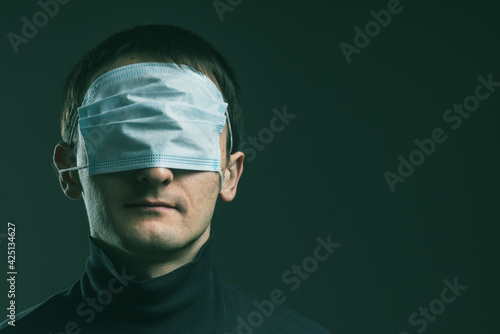 Man with med mask on his eyes. Concept of anti vaxxer and disinformation during global virus pandemic. Face portrait. Copy space.