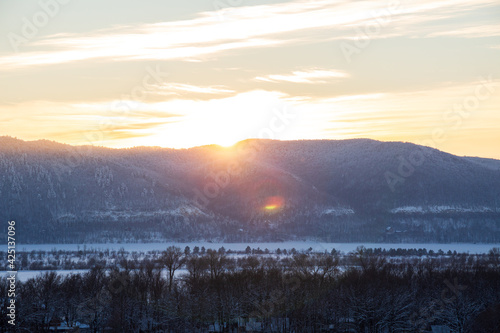 sunshine over the snow mountains near frozen river 