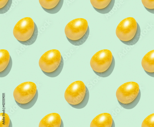 Easter pattern with golden eggs on pastel green background. Top view.