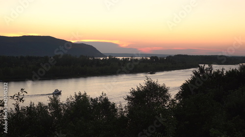 View of the mountains and the river at sunset. View from a hill. Boats float on the river.