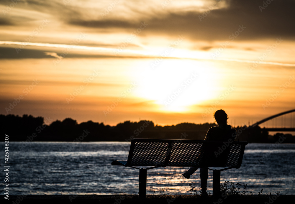 silhouette of a person sitting on a bench at sunset