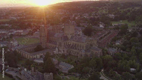 Wells, Somerset / United Kingdom (UK) - June 2020: Tracking aerial shot of Wells Cathedral with the sun setting in the background photo