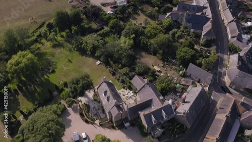 Aerial shot of traditional idyllic English village on a summer's day - starting from the church cemetery and tilting up towards the village - Abbotsbury, Dorset