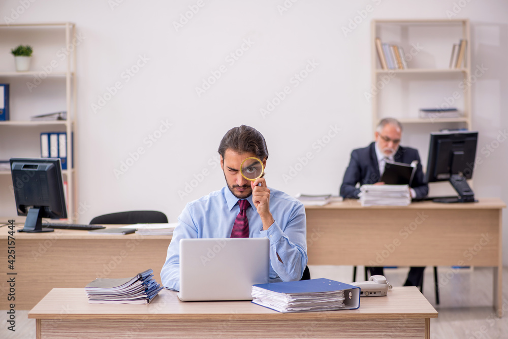 Old male boss and young employee working in the office Old male boss and young employee working in the office