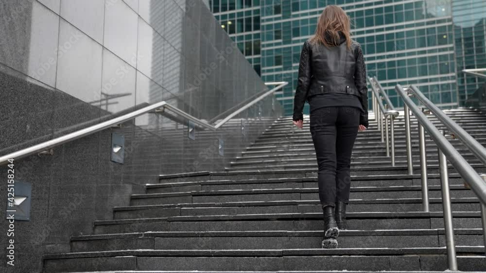young townswoman dressed black clothes is walking in modern district of big city young townswoman dressed black clothes is walking in modern district of big city
